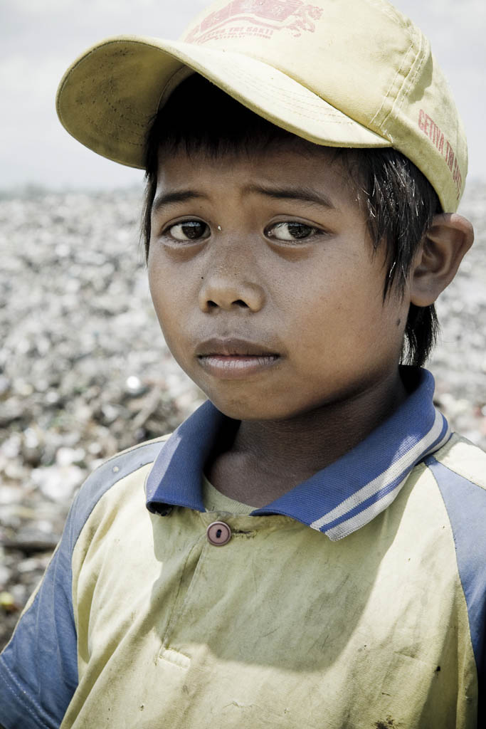 Anguish-faced child in revulsion at the stench of garbage. Makkasar dump. Indonesia.